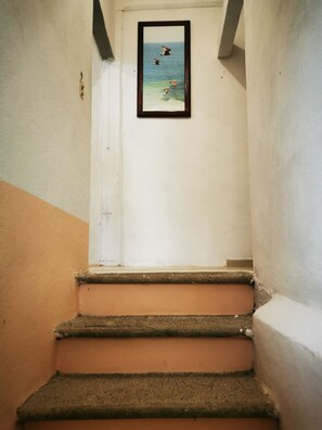 A staircase leading to a room with a framed picture of a beach scene.