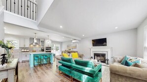 A spacious living area with a kitchen, a fireplace, and a high ceiling. - Pocono’s Mountain winter getaway! (Tobyhanna)