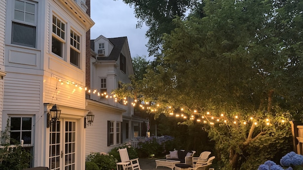 Een terras met buitenmeubilair, lichtjes en een overdekte barbecue.
