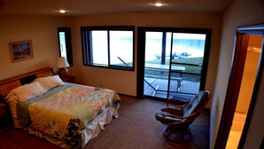 A bedroom with a bed, a chair, and a view of a patio with a table and chairs.