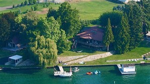 An aerial view of a lakeside property with a house, dock, and boats.