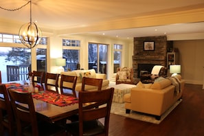 A spacious living room with a fireplace, a dining area with wooden chairs and a table, and a cozy seating area with a sofa and armchairs.