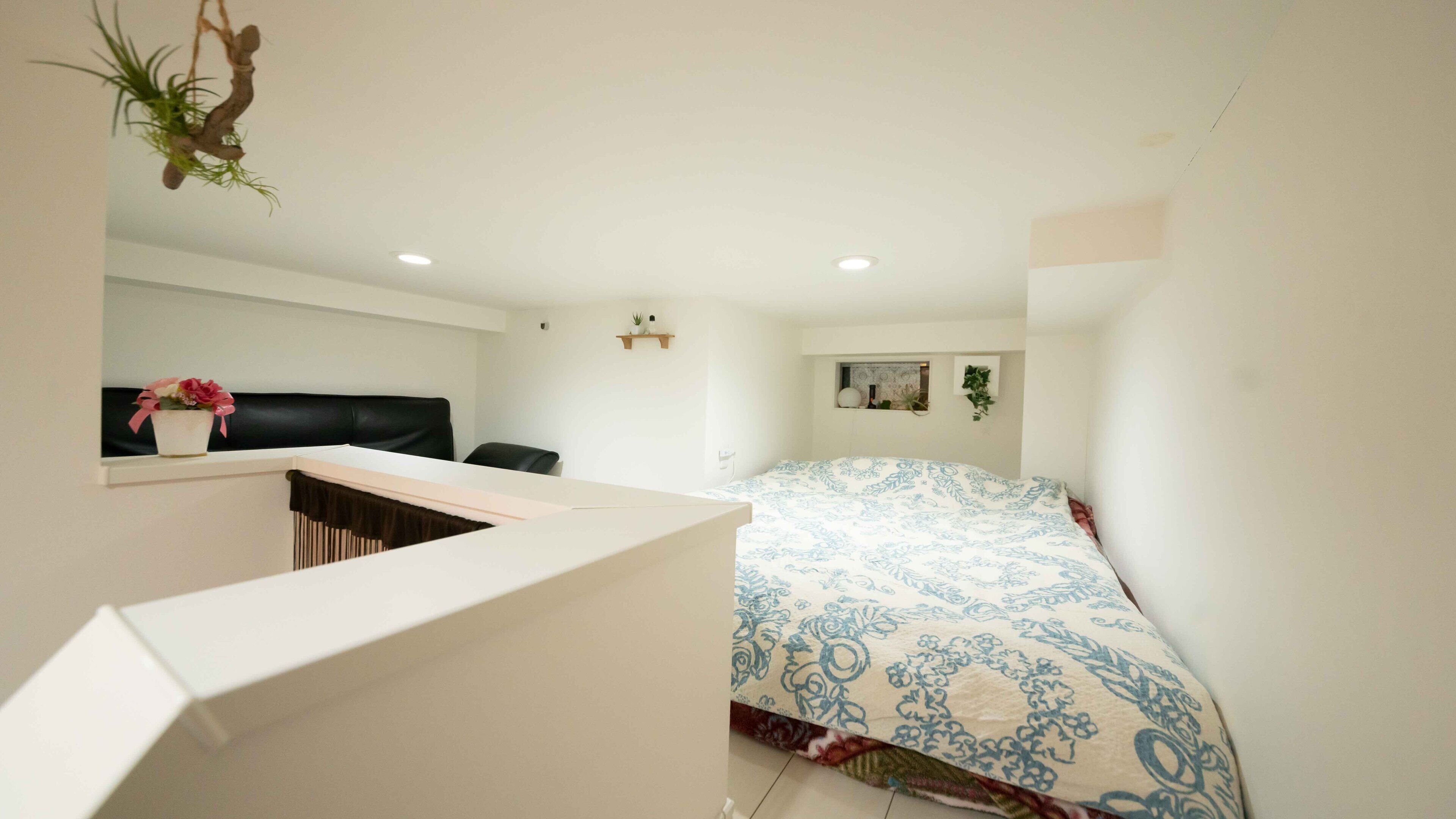 Un dormitorio con cama, escritorio y silla. Se ve una ventana con vistas al exterior.