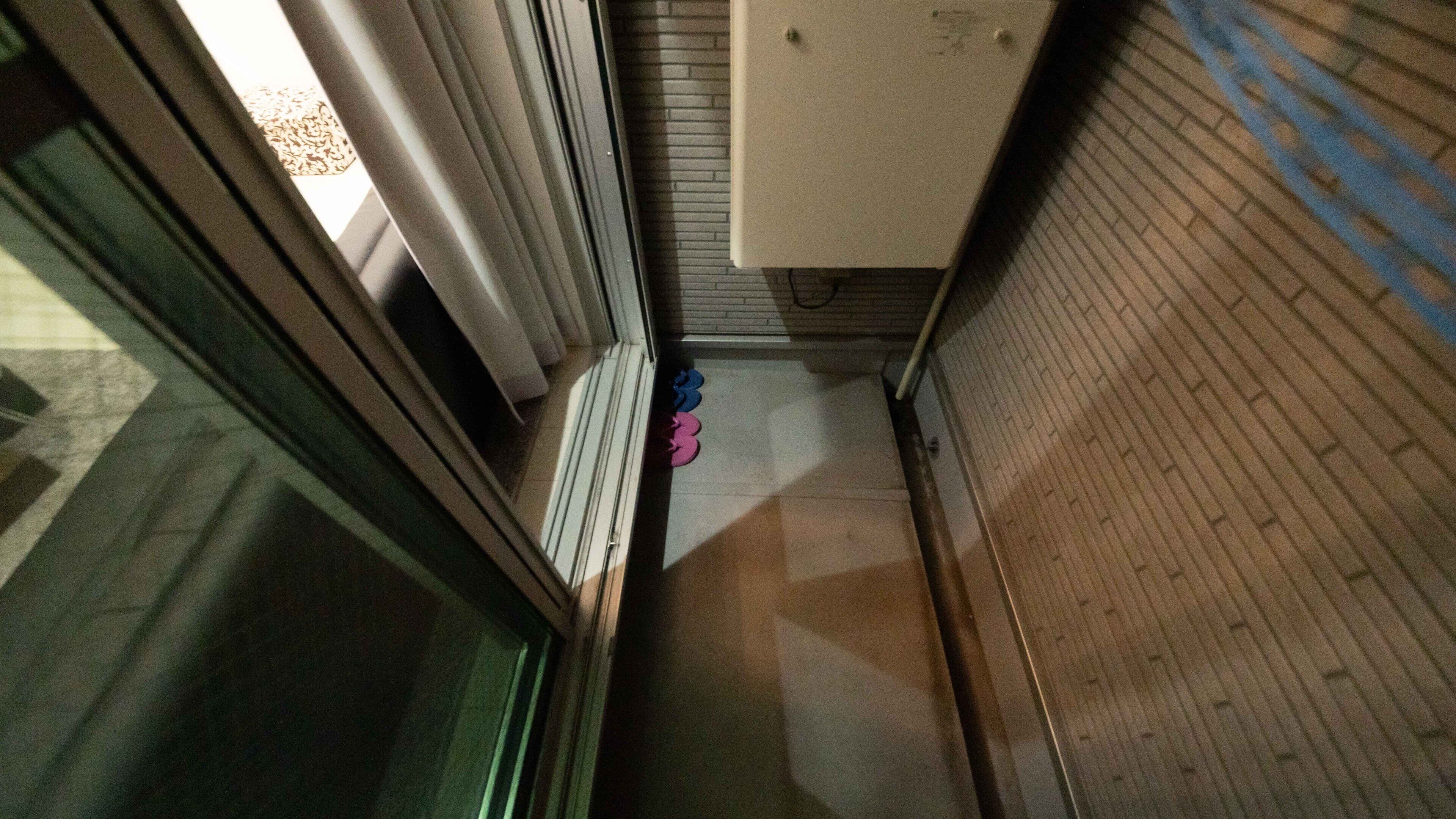 A narrow hallway with a door on the left and a white cabinet on the right.
