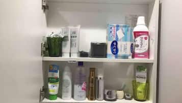 A bathroom cabinet with various toiletries including a green bottle labeled 'Aznes', a white bottle labeled 'NONIO', and a pink bottle labeled 'NANON'.
