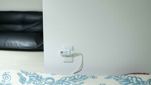 A white power outlet on a wall with a cable plugged in. - Polaris 101 (Nagoya)