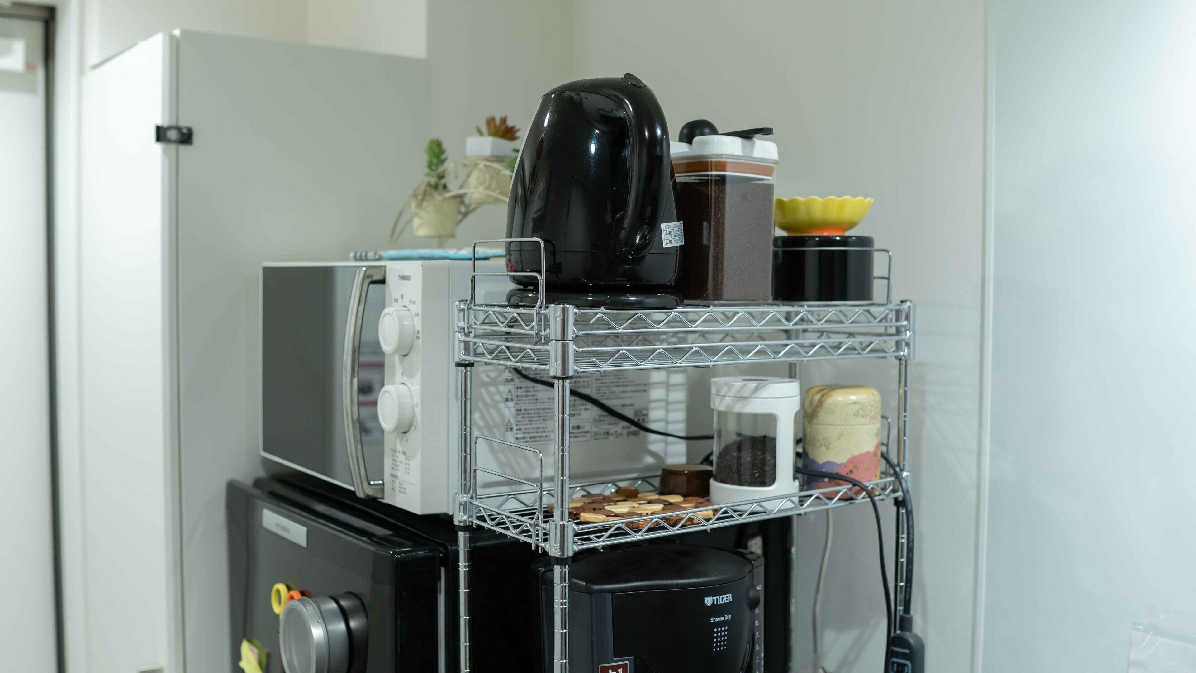 A kitchen with a coffee maker, a kettle, and a toaster on a metal shelf.