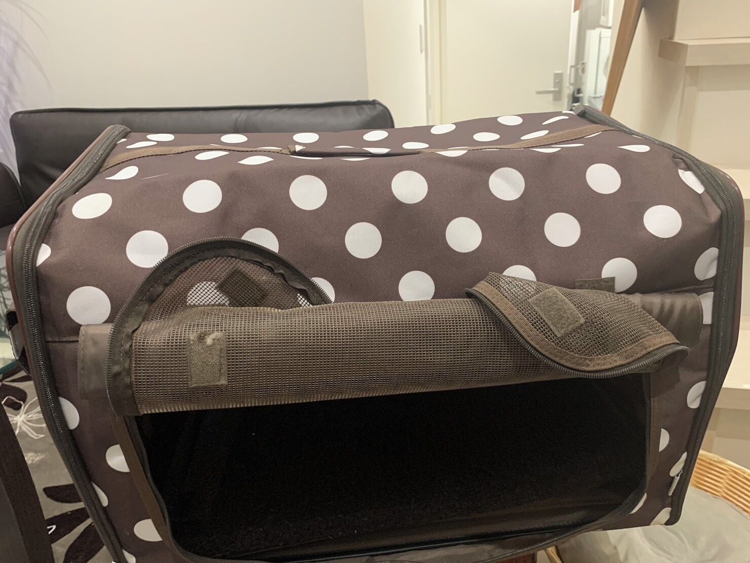 A polka-dotted bag with a mesh pocket, placed on a chair.