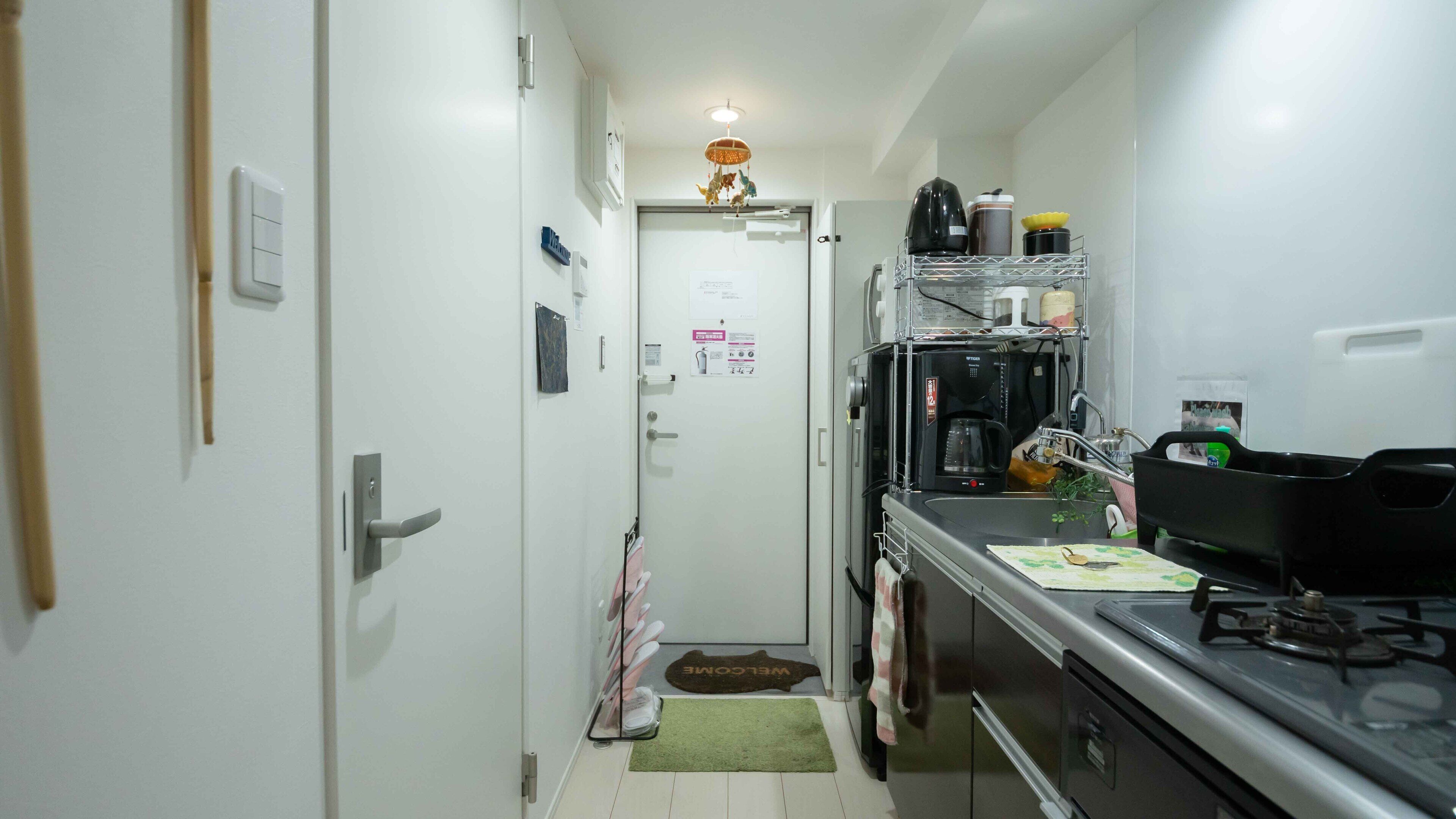 Een kleine keuken met een koffieapparaat, een spoelbak en een fornuis.