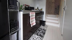 Una cucina moderna con un frigorifero nero, un fornello e un lavello. Un asciugamano a righe è appeso alla maniglia del forno.