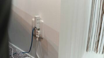 A white electrical outlet with a blue cable plugged in, located on a wall with a textured finish.