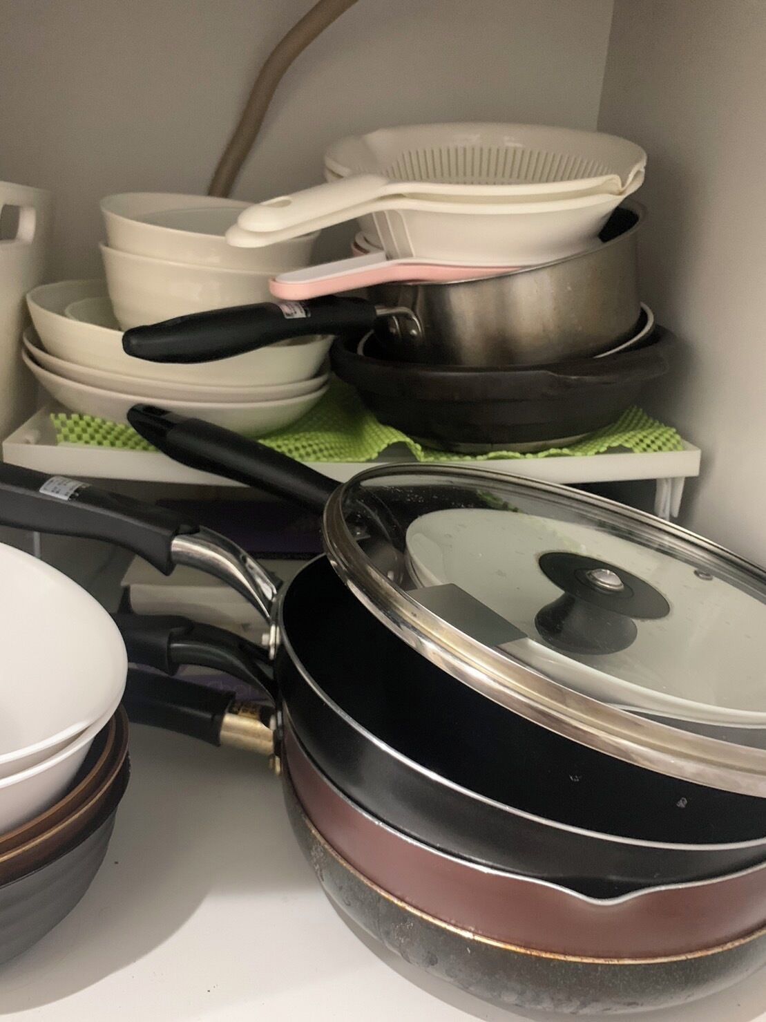Een keuken met diverse kookgerei, waaronder pannen, braadpannen en een koekenpan.