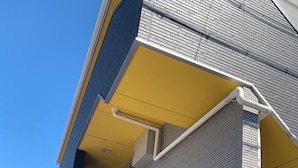 Un edificio con toldo amarillo, un tablón de anuncios y un cartel con información de contacto.