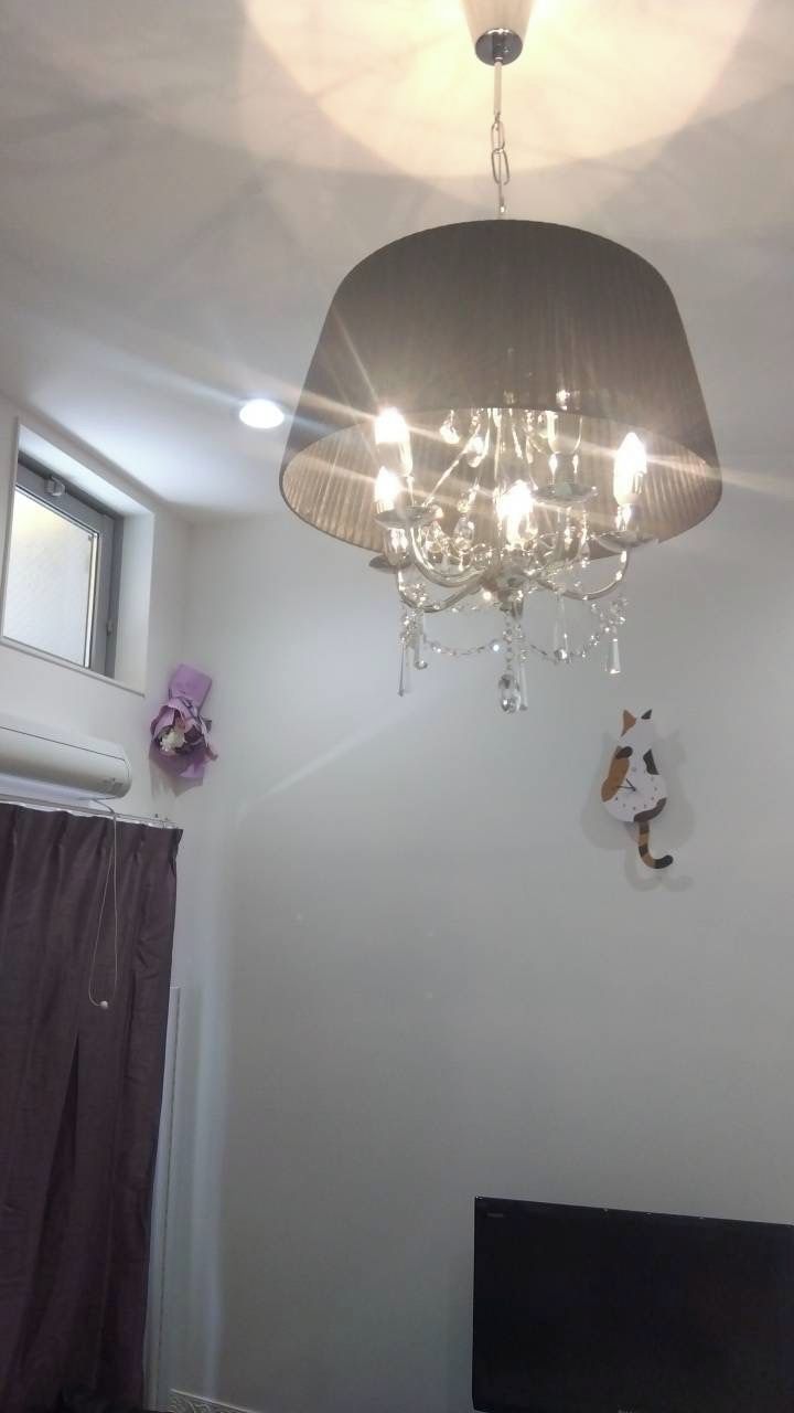 A room with a chandelier, a window, a curtain, and a wall-mounted decoration.