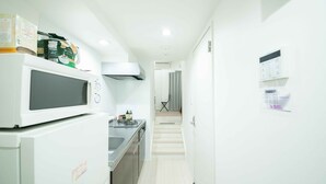 Cocina moderna con microondas, estufa y lavamanos. Una escalera conduce a un baño con ducha.