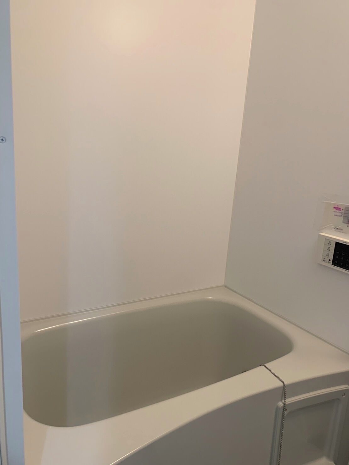 A modern bathroom with a freestanding bathtub, a wall-mounted heater, and a small shelf with toiletries.