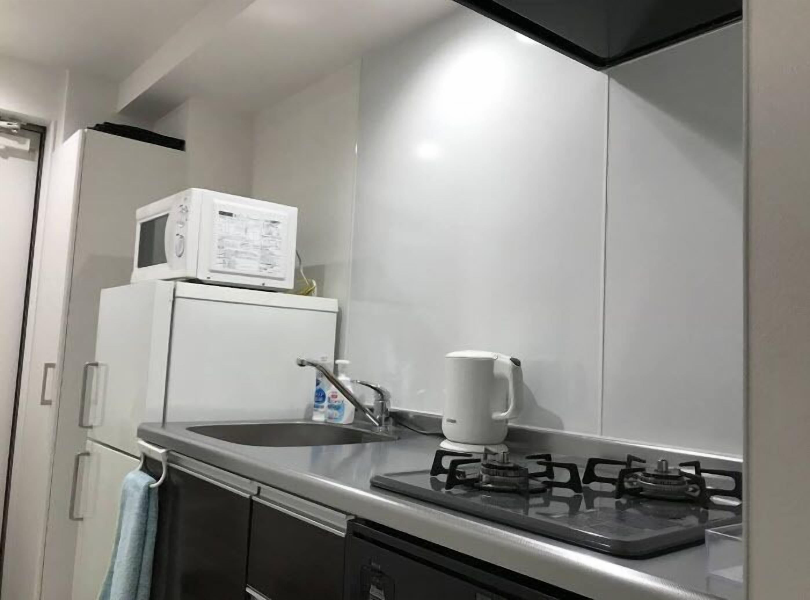 A compact kitchen with a microwave, sink, and gas stove.