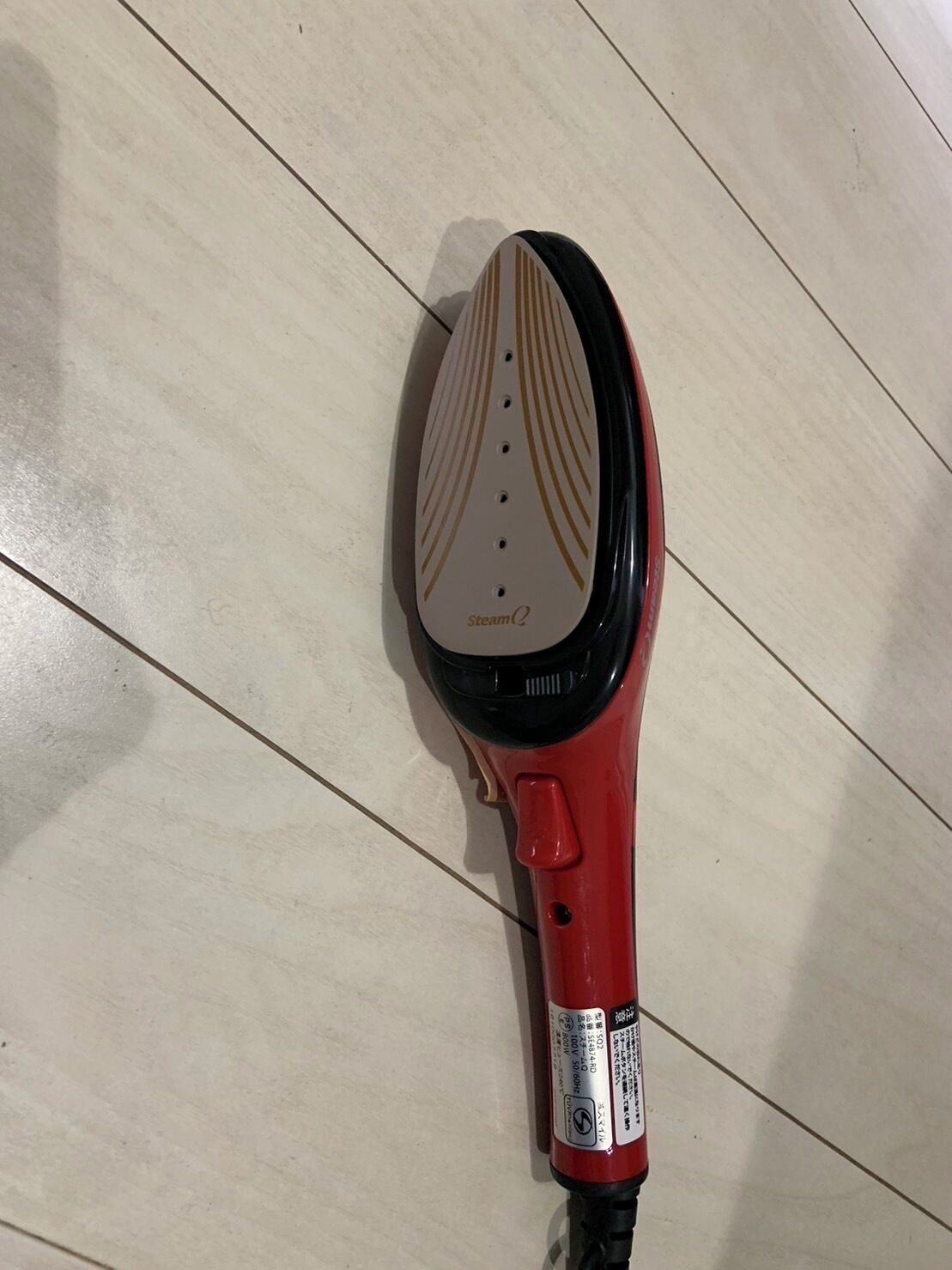 Un secador rojo con diseño blanco y dorado sobre un suelo de baldosas.