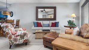 Una sala de estar con sofá, sillón, reposapiés y una mesa de centro.