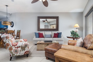 A living room with a sofa, armchair, ottoman, and a coffee table.