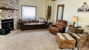 A living room with a stone fireplace, leather furniture, and a ceiling fan. - Secluded Farm near Bennett Springs State Park, 66 Robin Ln Tunas, MO 65764 (Lebanon)