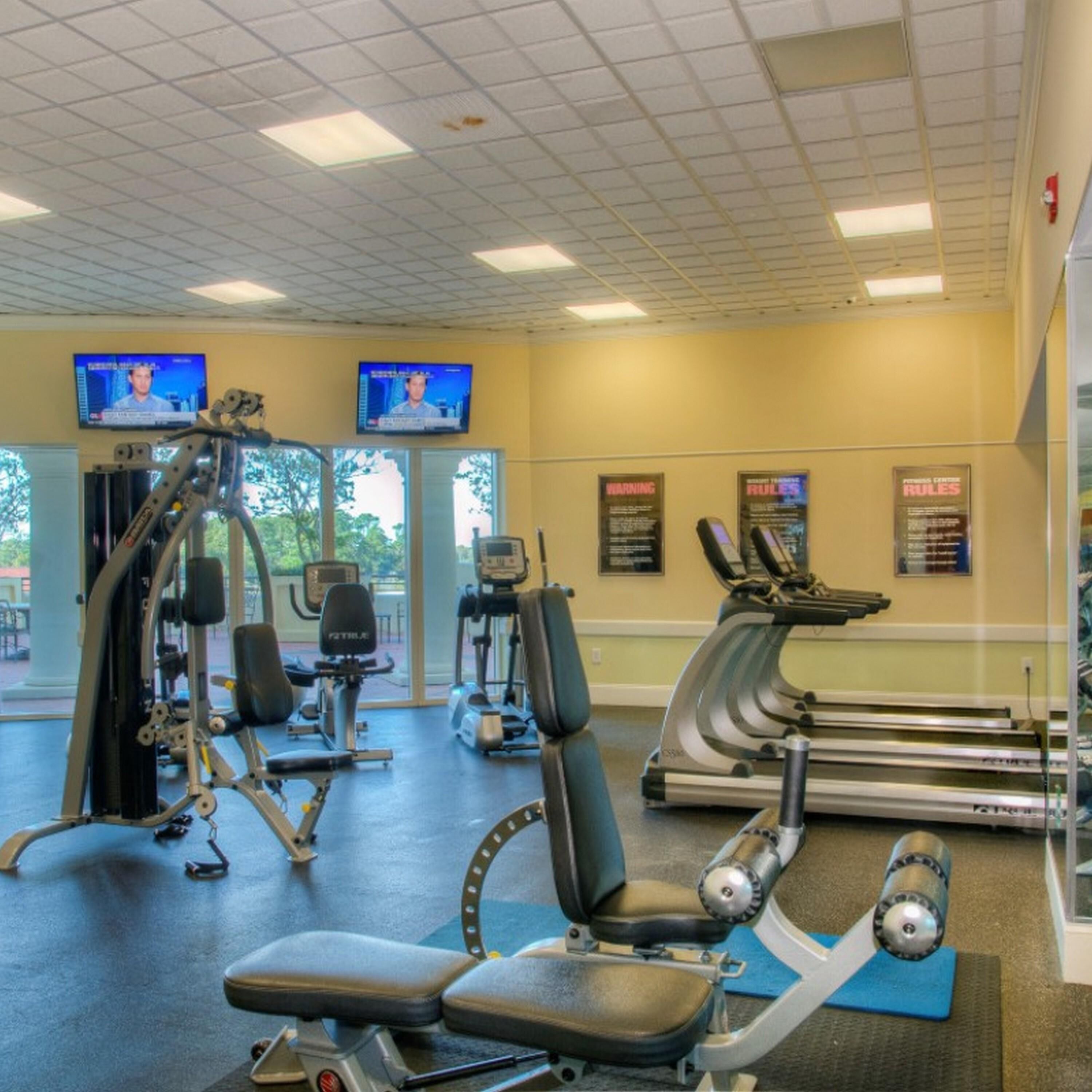 Ein Fitnessstudio mit Cardiogeräten, Krafttrainingsgeräten und Trainingsmatten.