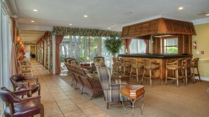 A spacious lobby with a bar area, wicker furniture, and large windows. - Ocean Creek Resort by Palmetto Vacations (Myrtle Beach)