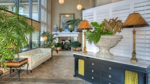 A spacious lobby with a sofa, potted plants, a fireplace, and a decorative console table. - Ocean Creek Resort by Palmetto Vacations (Myrtle Beach)