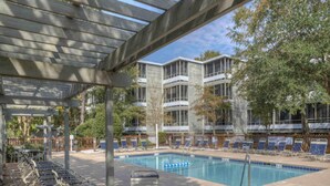 A pool area with lounge chairs and a covered seating area. - Ocean Creek Resort by Palmetto Vacations (Myrtle Beach)