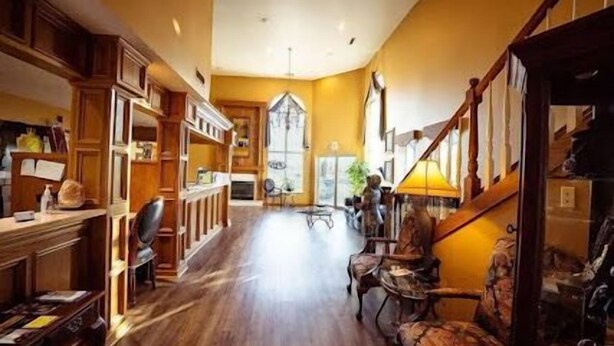 A spacious interior with wooden flooring, a staircase, and a seating area with chairs.