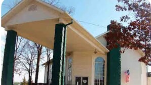A building with a covered entrance, a flag, and a clear sky.