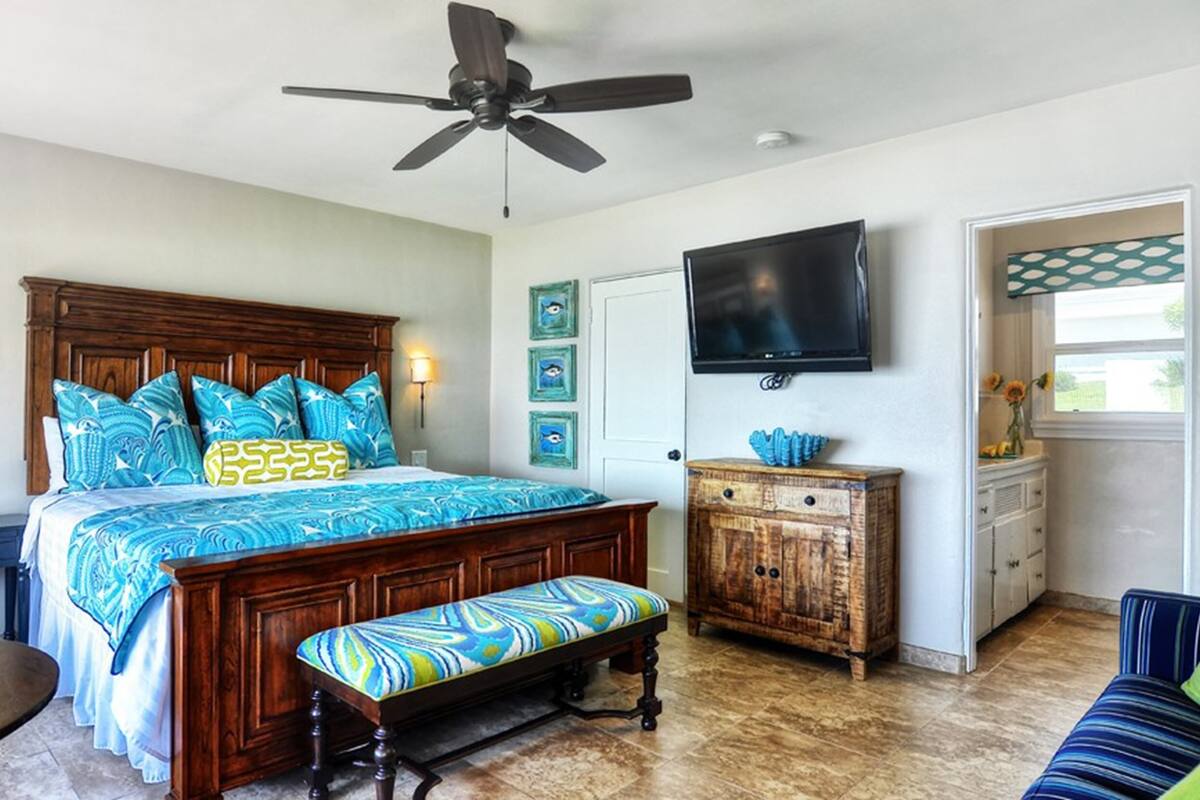A bedroom with a wooden bed, a bench, a TV, and a cabinet.