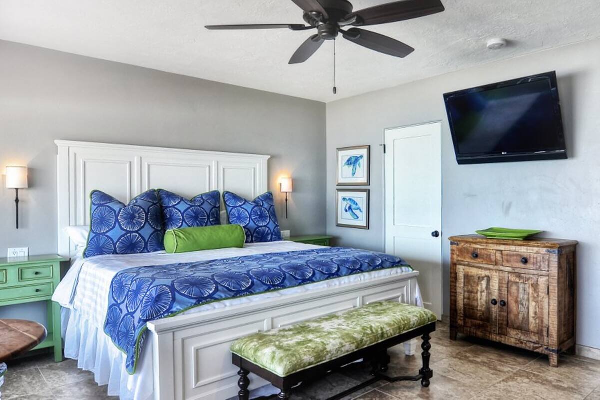 A bedroom with a bed, a wooden cabinet, a television, and a window.