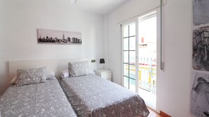 A bedroom with two beds, a cityscape artwork, a nightstand, and a balcony with a railing. - 1155 Apartment SanJuan 18 (Nerja)
