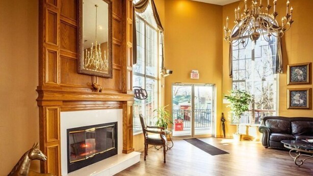 A spacious lobby with a fireplace, a chandelier, and a black leather sofa.