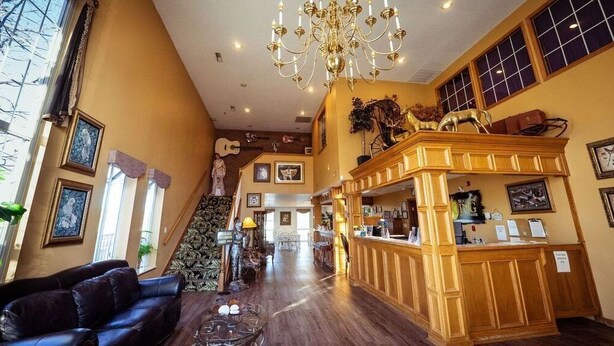 A spacious lobby with a grand chandelier, a reception desk, and a staircase leading to an upper level.