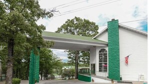 A building with a green entrance canopy, a white exterior, and an American flag.