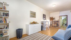 Un salon comprenant un canapé, une table basse, une bibliothèque, un meuble blanc et un tapis à rayures.