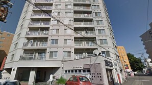 A multi-story residential building with balconies, a gated entrance, and a parking area. - Sapporo-ENJU Nakanoshima 204 (Sapporo)