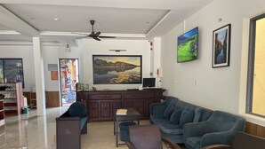 A modern living room with a sofa, chairs, a coffee table, and a TV. - Thuong Da Riverside Homestay (Da Nang)