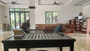 A spacious room with a large table, a bench, and a bookshelf. - Thuong Da Riverside Homestay (Da Nang)