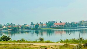 A lakeside view with buildings in the background and a clear sky. - Thuong Da Riverside Homestay (Da Nang)