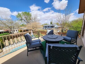 A balcony with a round table and two chairs, a view of a residential area, and a clear blue sky. - Lake Powell Home with Pool (Page)