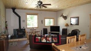 A cozy living room with a fireplace, wooden furniture, and a mounted deer head on the wall.