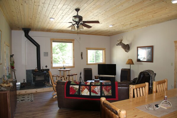 A cozy living room with a fireplace, wooden furniture, and a mounted deer head on the wall.