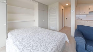 Un dormitorio con cama, armario y kitchenette.