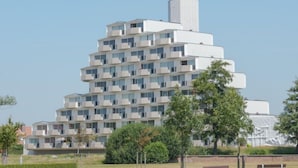 Un edificio moderno de varios pisos con un diseño escalonado singular, que cuenta con balcones y ventanas amplias.