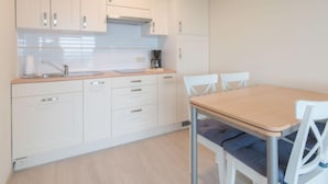 Una cocina moderna con armarios blancos, encimera de madera y una mesa de comedor con sillas blancas.