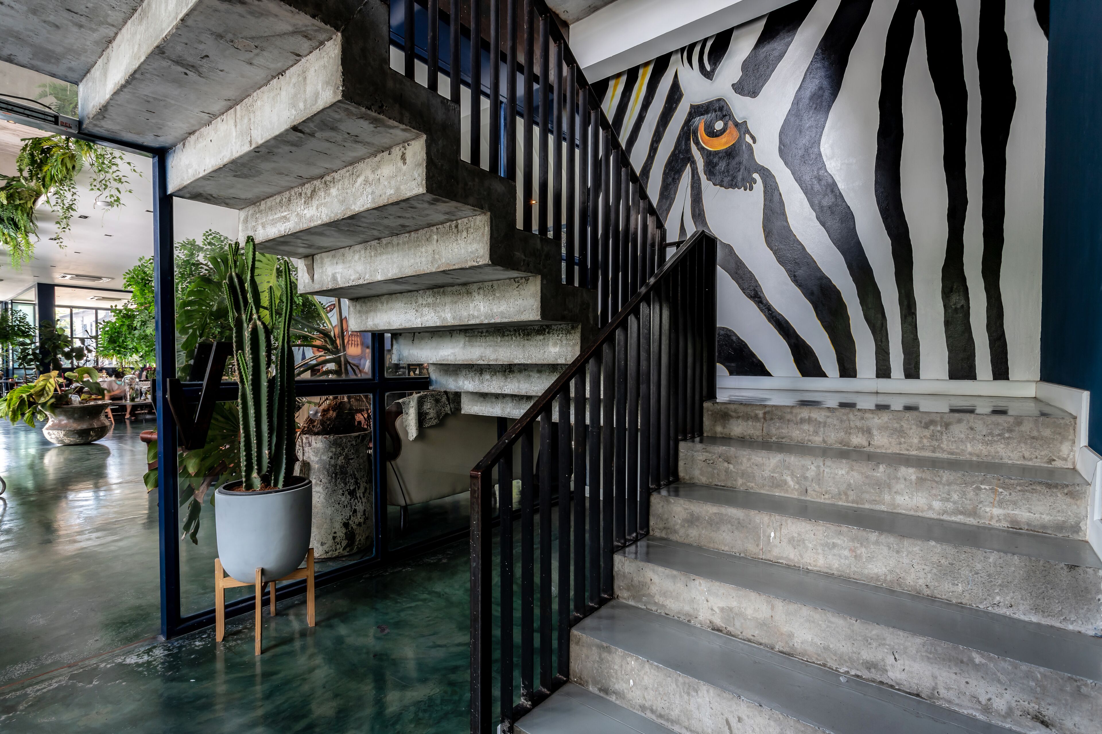 A staircase with a zebra mural, concrete steps, and potted plants.