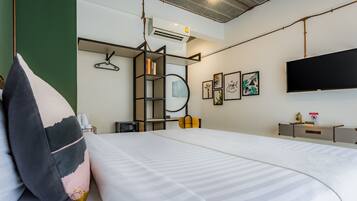 Une chambre d’hôtel moderne dotée d’un grand lit, d’un téléviseur fixé au mur, d’une bibliothèque et d’un climatiseur mural.